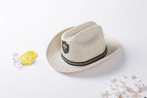 Close-up of ivory straw sun hat with printed ribbon and summer beach decorations