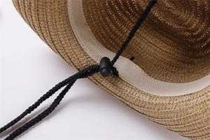 Close-up of woven straw texture with adjustable black windproof chin strap and cord lock