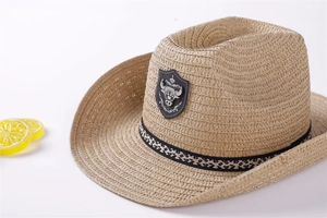 Close-up of woven straw fedora hat featuring a metal bull head badge and patterned band