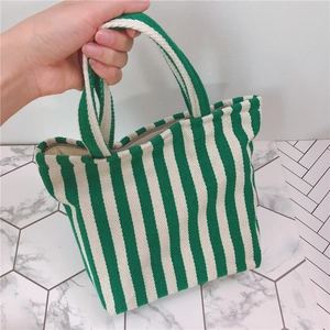 Detailed view of green and white vertical striped canvas bag with secure metal zipper