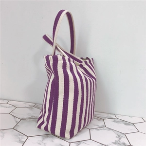 Detailed side view of a durable purple and white striped canvas handbag with wide handles