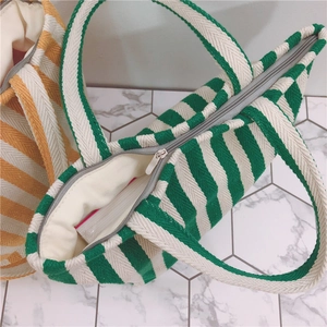 Detail of striped canvas tote bags showing textured fabric and smooth zipper closure