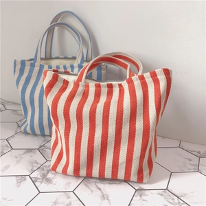 Close-up of thick canvas tote bags with blue and orange vertical stripes on marble floor