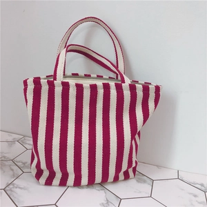 Detail of red and white striped canvas tote bag with reinforced handles and durable texture