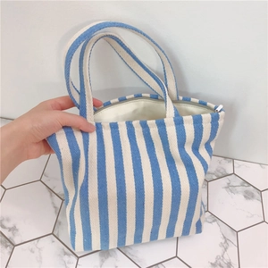Detail of blue and white striped thick canvas tote bag featuring metal zipper and handles