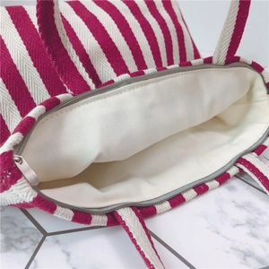 Detail of a red and white striped canvas tote bag with a secure metal zipper closure