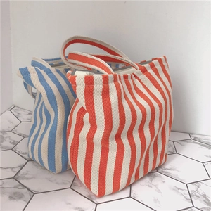 Close-up of durable herringbone canvas texture on orange and blue striped tote bags