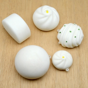 5-piece simulation steamed bun squishy toy set with keychain attachment on wood surface