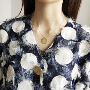 Close-up of a gold-plated round medallion pendant with intricate geometric engraving