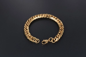 Detailed close-up of a gold flat chain bracelet featuring a secure spring ring clasp