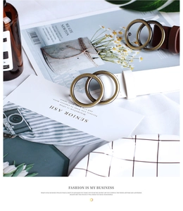 Detailed view of women's round buckle belts in white and brown with bronze double rings