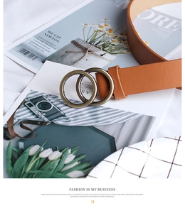 Detail of a brown leather belt with vintage bronze double round buckles on a stylish layout