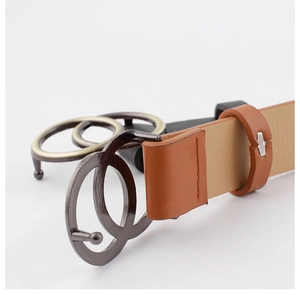 Detail of the interlocking round buckles in gold and black on a brown leather belt