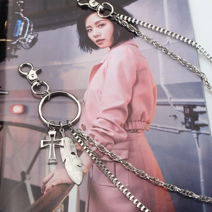 Detail of silver multi-layer trouser chain with cross and feather pendants on magazine