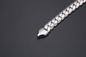 Macro shot of silver stainless steel flat Cuban link bracelet with polished clasp detail
