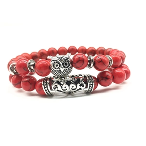 Detail of red textured beads and silver owl charm on an ethnic style beaded bracelet