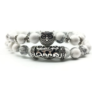 Detailed view of beaded bracelet set with owl charm and white marble texture beads