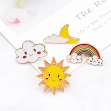Dettaglio del set di 4 spille smaltate con motivi di sole, luna e nuvole arcobaleno