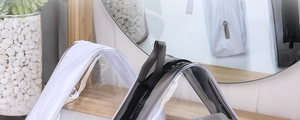 Close-up of clear PVC cosmetic bags with black and white trim on a wooden table