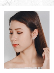 Detail showing leaf-shaped earrings with light blue teardrop pendants on model