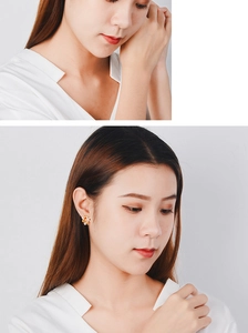 Detail shot of a golden flower stud earring with small white pearls on a model ear