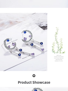 Detail of silver crescent moon earrings with blue zircons and long metallic drops