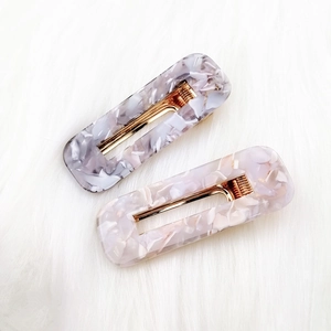 Detail view of rectangular marble texture acetate hair clips with golden metal spring clips