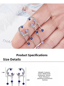 Detail view of crescent moon tassel earrings with sparkling blue zircons in white gold finish