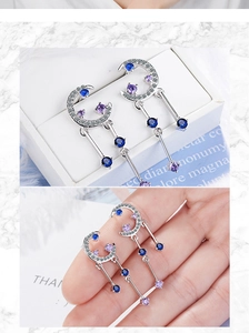 Detailed shot of silver crescent moon earrings with blue and purple zirconia gemstones