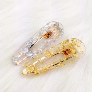 Detail of transparent resin hair clips with embedded gold and silver metallic foils