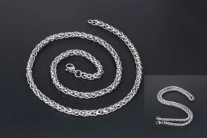 Macro shot of silver stainless steel wheat chain with detailed braided texture on black