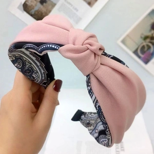 Cerchietto in tessuto rosa con nodo e fodera paisley mostrato in un primo piano curato