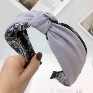 Dettaglio della fascia lilla con nodo a contrasto e motivo paisley nero e bianco