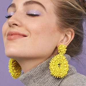 Bohemian large yellow beaded earrings styled on model with a vibrant purple background