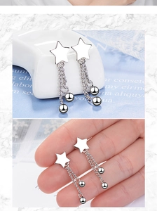 Detail of star-shaped silver drop earrings with long chain tassels and bead ends