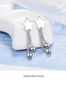 Macro shot of silver star-shaped drop earrings with tassel chains and beads