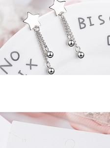 Detail of silver star tassel earrings with delicate chains and small metal beads finish
