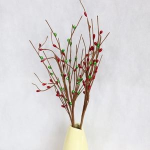 Artificial berry branches with red and green fruits in a vase for home holiday decoration