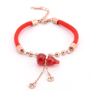 Dettaglio bracciale in corda rossa con ciondoli in oro rosa e pendente a forma di zucca