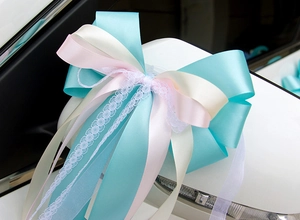 Détail d'un nœud décoratif en dentelle et ruban de satin sur un miroir de voiture