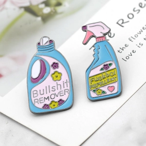 Macro detail of enamel pins featuring Bullshit Remover and Fuckboy Repellent text