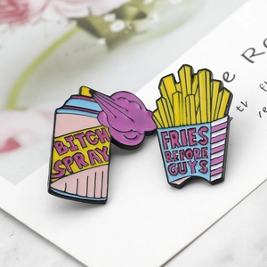 Detail of enamel pins featuring Bitch Spray and Fries Before Guys designs with floral accents