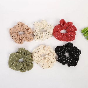 Close-up of six colorful polka dot hair scrunchies in chiffon fabric on white background