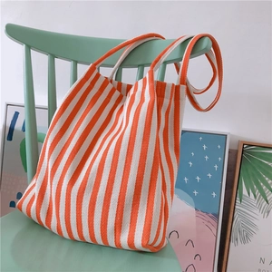Detail of orange and white vertical striped canvas tote bag hanging on a chair