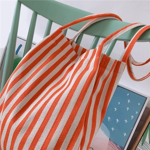 Detail of orange and white diagonal striped canvas tote bag hanging on a green chair