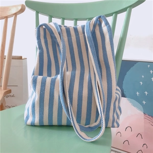 Close-up of blue and white striped canvas tote bag on a rustic wooden chair