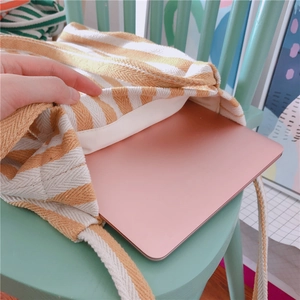 Detail showing the inner space of a yellow striped canvas bag holding a pink laptop