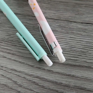 Close-up of pink and green cartoon mechanical pencils with erasers on a wooden table