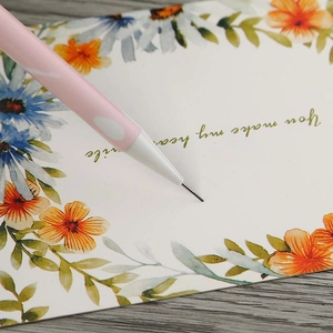 Detailed view of pink mechanical pencil writing on a floral greeting card