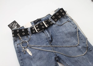 Detail of light blue jeans with black double grommet canvas belt and silver layered chains